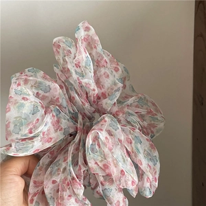Close-up of lightweight floral organza scrunchie with soft pink and blue flower patterns