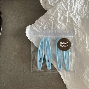 Détail de 4 barrettes bleues claires dans leur sachet transparent avec étiquette fait main
