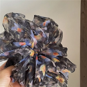 Detail of a large sheer organza scrunchie with colorful abstract floral patterns