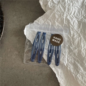 Lot de quatre barrettes bleues foncées dans un sachet transparent avec étiquette ronde