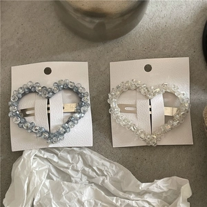 Detalle de pinzas para el cabello con cuentas de cristal en forma de corazón azul y claro
