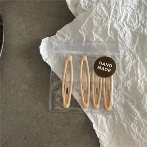 Détail de 4 barrettes à cheveux couleur crème dans un emballage avec étiquette faite main