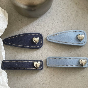 Detail of denim fabric hair clips with textured silver metal hearts in blue shades