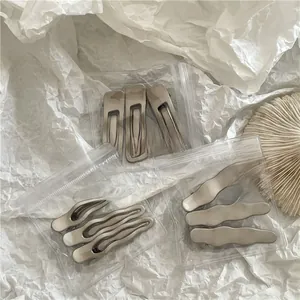 Macro view of three matte silver hair clips with brushed metal texture in packaging
