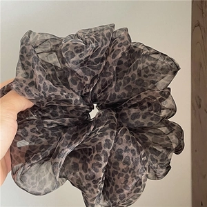 Macro shot of an oversized leopard print mesh scrunchie showing sheer fabric detail
