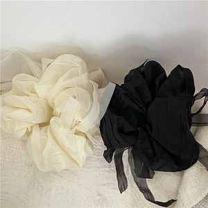 Detail view of oversized pleated organza scrunchies in beige and black with ribbons