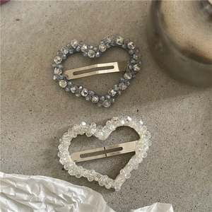 Detalle de pinzas para el cabello con cuentas de cristal en forma de corazón, blanco y gris