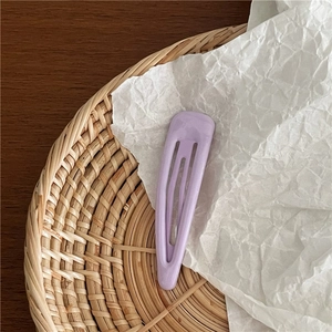 Barrette goutte d'eau mauve mat sur papier blanc et plateau tressé en détail