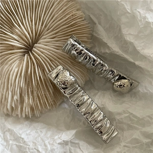 Detailed macro of silver metallic hair clips with irregular textured surface and patterns