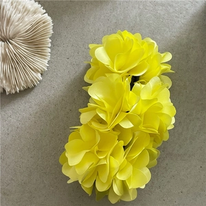 Macro detail of large yellow flower hair clip with realistic satin petals for summer styling