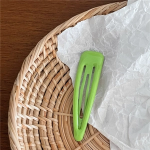 Gros plan sur la barrette BB rectangulaire verte ajourée sur fond à texture naturelle