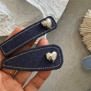Detailed view of denim fabric hair clips with contrast stitching and hammered metal hearts