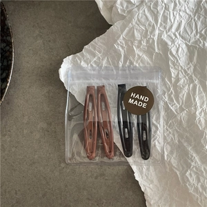 Vue détaillée de 4 barrettes mates marron et noir dans une pochette zippée transparente
