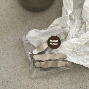 Detailed view of three matte champagne metal wavy hair clips in handmade packaging