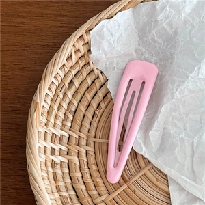 Gros plan d'une barrette BB rose brillante en forme de goutte avec texture lisse