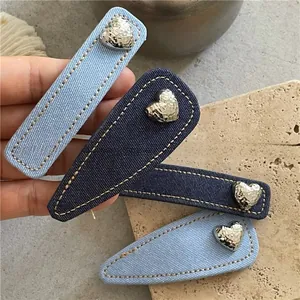 Detailed close-up of denim fabric hair clips with yellow stitching and silver heart charms