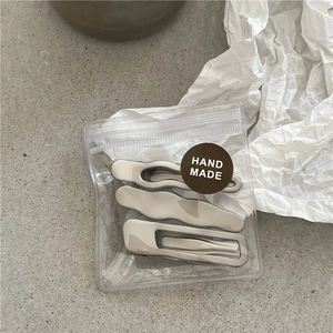 Detailed view of three silver wave metal hair clips in handmade craft packaging