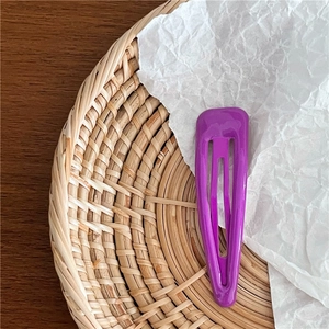 Vue détaillée d'une pince à cheveux goutte d'eau violette sur un fond décoratif texturé