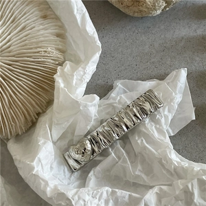 Silver rectangular metal hair clip with crinkle texture and heart detail on white coral