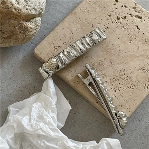 Detail of silver rectangle hair clips with textured metal surface and heart accent