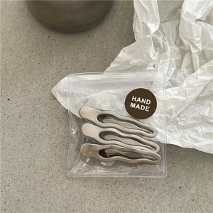 Three-piece set of silver wavy metal hair clips packaged with a Hand Made label detail