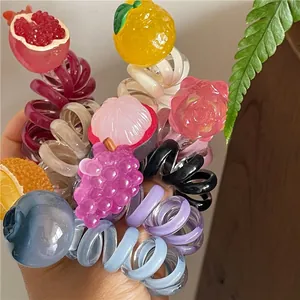 Dettaglio degli elastici per capelli a filo telefonico con piccoli frutti colorati