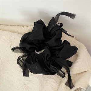 Detail shot of a black chiffon hair scrunchie with long ribbons and a sheer bow design