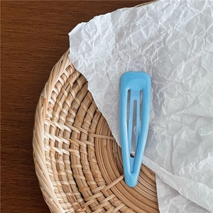Gros plan d'une barrette goutte d'eau bleu clair mat sur un fond de papier blanc texturé