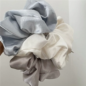 Close-up showing the soft satin texture of light blue, beige and champagne scrunchies