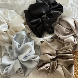 Silky satin scrunchies set in neutral colors including black, white, and champagne tones