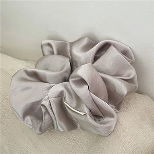 Close-up of a premium champagne oversized satin scrunchie with elegant silk folds