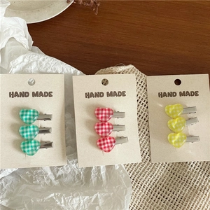 Detailed view of colorful heart-shaped gingham hair clips on a handmade card display