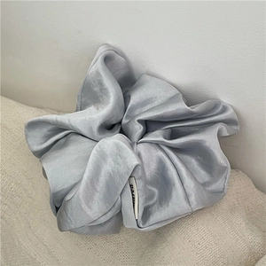 Close-up of a silver-gray large satin scrunchie with soft folds and elegant silk texture