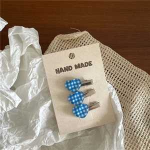 Three-piece set of blue checkered heart-shaped hair clips on a handmade card display