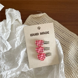 Three-piece set of heart-shaped hair clips with red and white checkered pattern detail