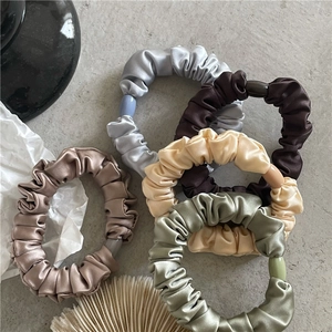 Set of five elegant satin silk scrunchies in muted tones with matching decorative accents
