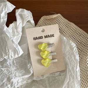 Close-up of three yellow checkerboard heart hair clips on handmade card display