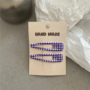Detail von violett-weiß karierten Haarklammern auf einer handgemachten Displaykarte