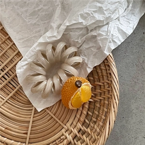 Dettaglio macro di un elastico a spirale bianco perlato con ciondolo a forma di durian