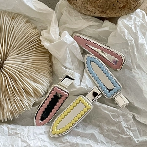 Détail de quatre pinces à cheveux ondulées argentées en rose, bleu, jaune et rouge
