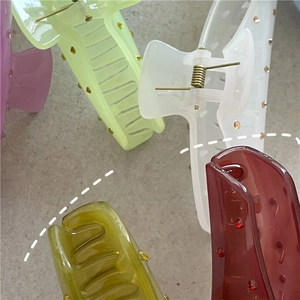 Dettaglio di fermagli per capelli traslucidi colorati con motivo a pois e molla in metallo