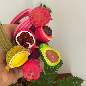 Close-up of 3D fruit hair ties featuring realistic dragon fruit, avocado and durian textures