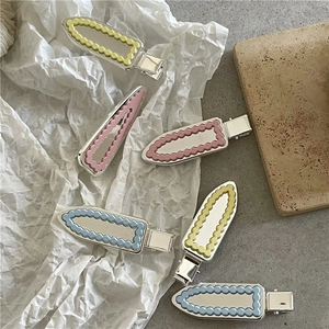 Vue détaillée de pinces à cheveux macaron colorées avec bords argentés ondulés