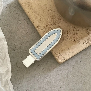 Détail de la pince à cheveux festonnée bleu clair avec insert miroir argenté sur pierre