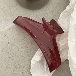 Dettaglio di una pinza per capelli bordeaux lucida con strass rossi su carta
