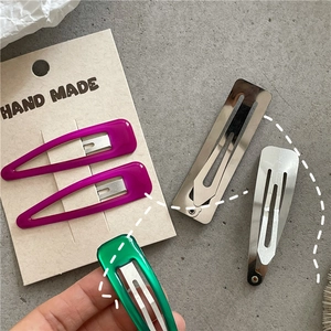 Detail of purple teardrop and green rectangular metal hair clips on handmade card