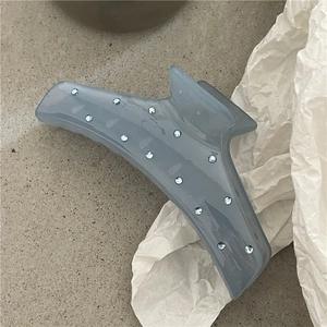 Dettaglio di molletta per capelli blu ghiaccio traslucido con strass su sfondo materico
