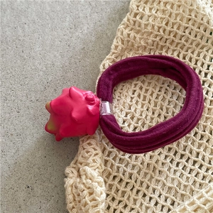 Close-up of pink dragon fruit hair tie with thick elastic band on a woven background