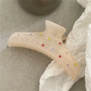 Dettaglio della pinza per capelli in resina crema con strass colorati e denti antiscivolo