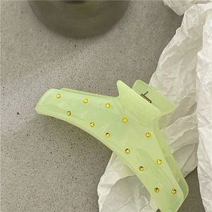 Dettaglio della molletta per capelli in resina verde chiaro con strass gialli e molla d'oro